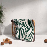 Forest green marble woven throw blanket for couch draped over a chair against a light gray wall.