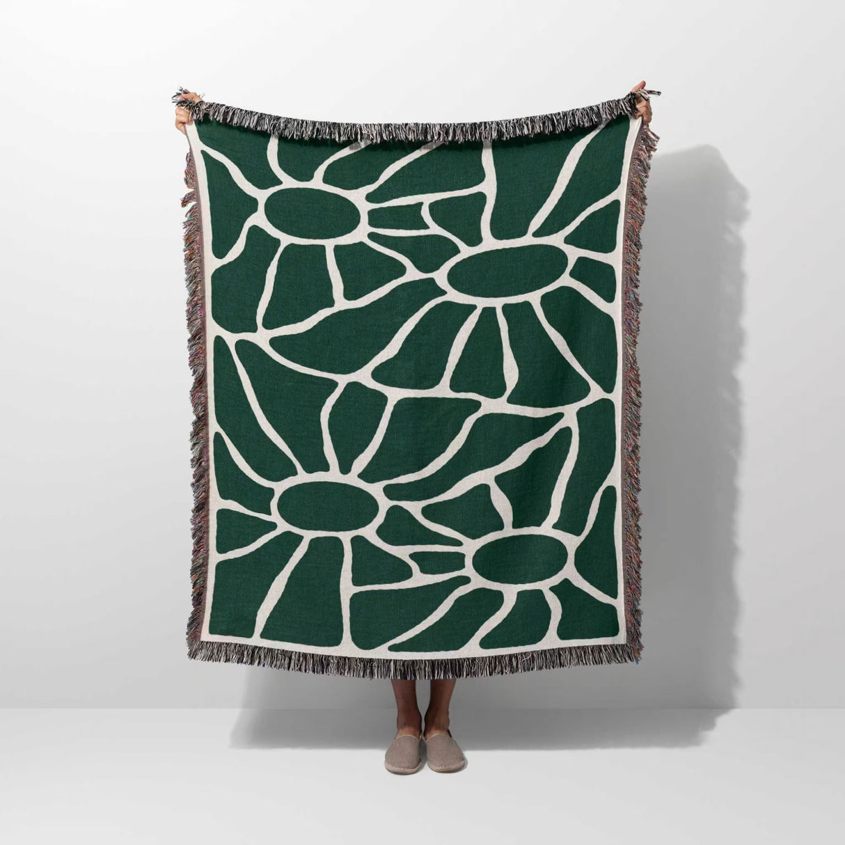 Forest green Matisse tapestry throw blanket for couch hold by a person on a plain background.