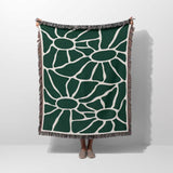 Forest green Matisse tapestry throw blanket for couch hold by a person on a plain background.