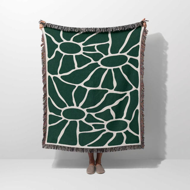 Forest green Matisse tapestry throw blanket for couch hold by a person on a plain background.