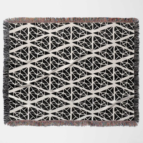 Geometric patterned woven blanket throw tapestry with black and white design flat lay on a plain background