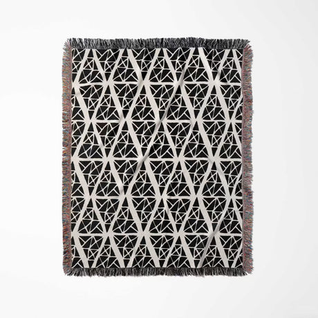 Geometric patterned woven blanket throw tapestry with black and white design full view on a light gray background.