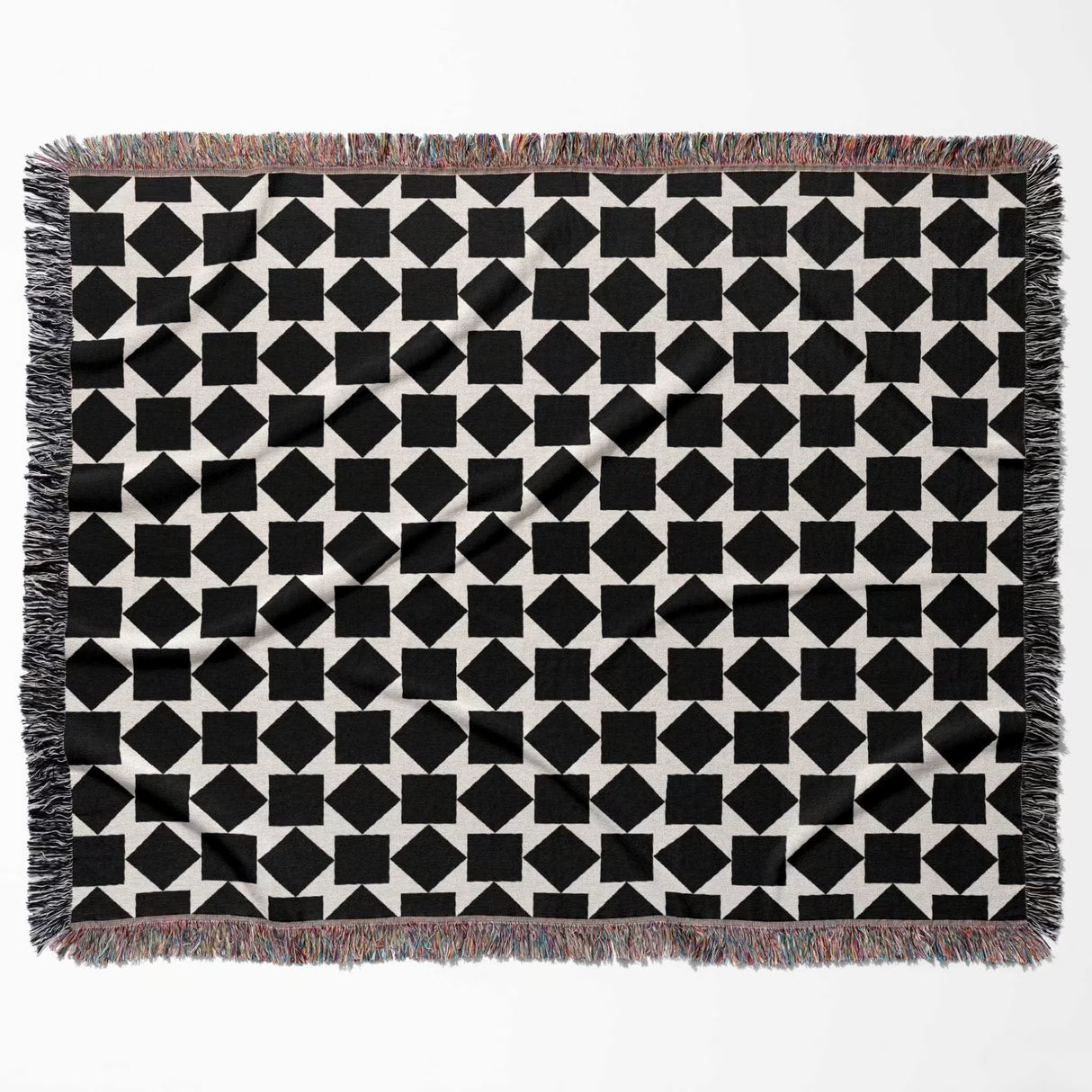 Black and white geometric square patterned woven blanket throw with fringed edges flat lay on a white background.