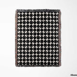 Black and white geometric square patterned woven blanket throw full view with fringe on a light gray background.