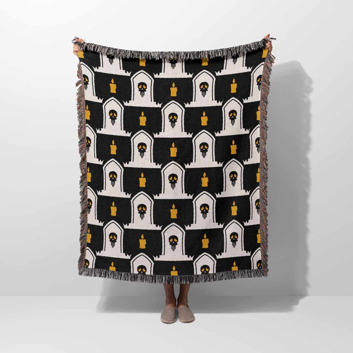 Black and white patterned throw blanket draped over a person on a white background