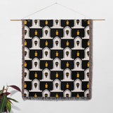 Decorative blanket with black, white, and gold pattern hanging on a wall.