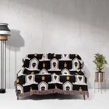 Black and white patterned throw blanket draped over a chair against a white wall.