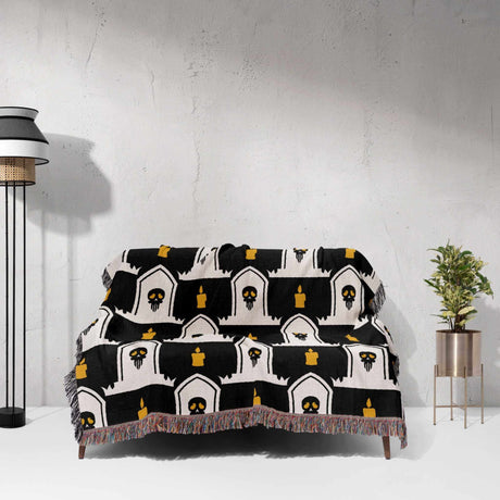 Black and white patterned throw blanket draped over a chair against a white wall.