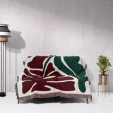Floral patterned Henri Matisse red flowers woven throw blanket draped over a chair against a white wall.