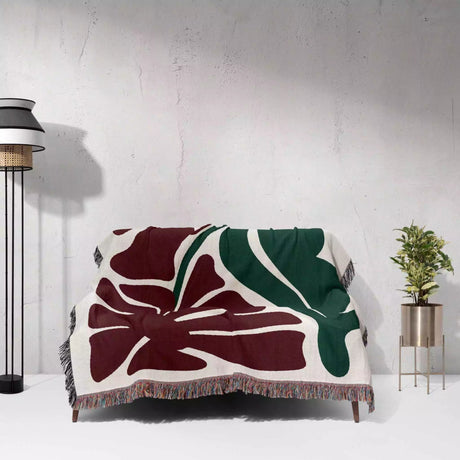Floral patterned Henri Matisse red flowers woven throw blanket draped over a chair against a white wall.