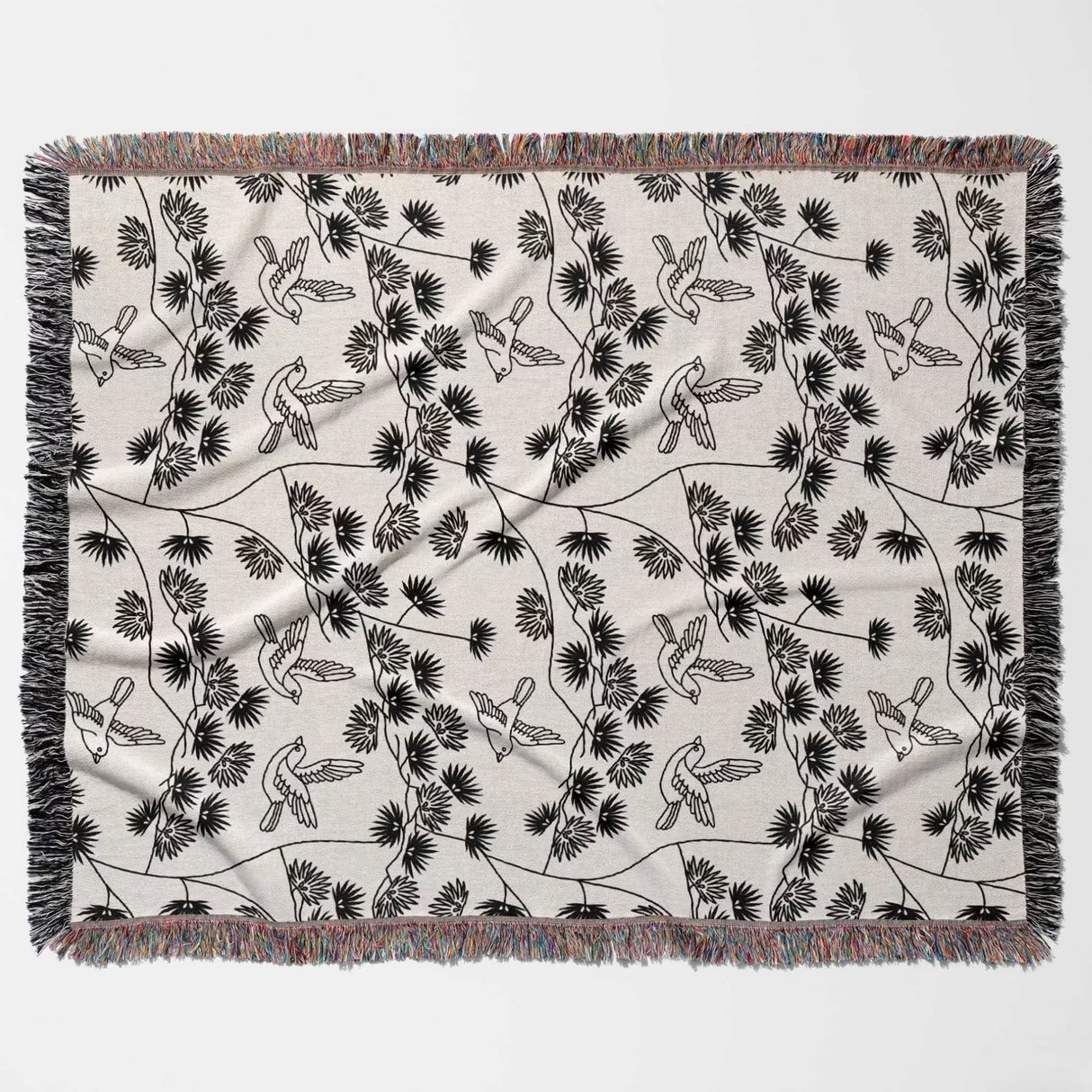 Japanese style woven blanket throw tapestry with black and white bird pattern flat lay on a gray background.