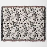 Japanese style woven blanket throw tapestry with black and white bird pattern flat lay on a gray background.