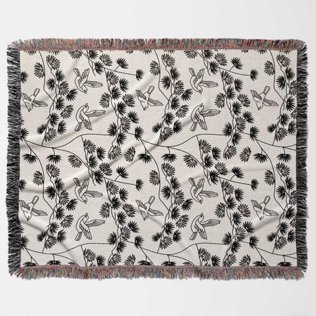Japanese style woven blanket throw tapestry with black and white bird pattern flat lay on a gray background.