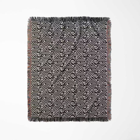 Black and white labyrinth hexagon pattern woven blanket throw with fringes full view on a white background.