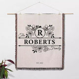 Personalized last name monogram blanket with 'The Roberts Family' design on a white wall.