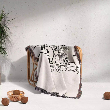 Last name monogram blanket with floral patterns and text draped over a chair on a light background