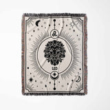 This image displays a vertical flat lay of a Leo Zodiac Blanket. The intricate black-and-white design features a majestic lion surrounded by celestial elements, making it ideal for home decor and astrology enthusiasts.