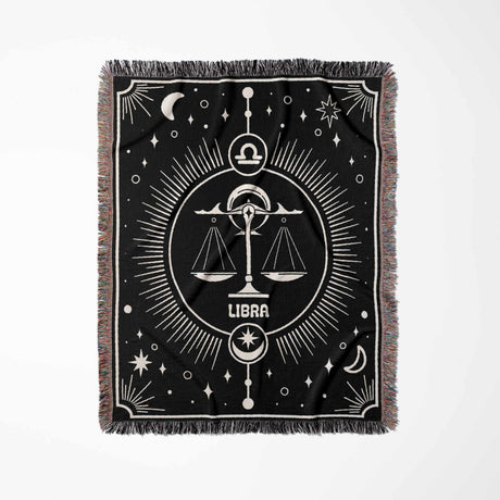 The Libra Zodiac Blanket displayed flat in a vertical orientation, highlighting the intricate woven details and the balance scales symbol of Libra, with decorative elements of the night sky and a multicolor fringe that frames the blanket.