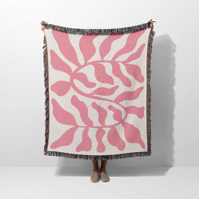 Lighter red leaf Matisse throw blanket held by a person on a white background