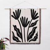 Matisse flowers black and white woven throw blanket as woven wall art with black leaf pattern on a white background