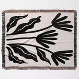 Matisse flowers black and white woven throw blanket with black leaf-like patterns on a beige background