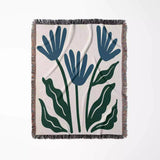 Floral-patterned Matisse inspired blue flowers woven throw blanket with blue and green leaves on a white background
