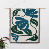 Matisse style blue floral cotton woven throw blanket as woven wall art with blue and green abstract design on a white background