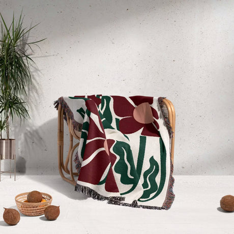 Decorative Matisse style blue pure cotton woven throw blanket with floral pattern draped over a chair against a light background