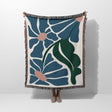 Matisse style floral cotton woven throw blanket for couch draped over a person on a white background