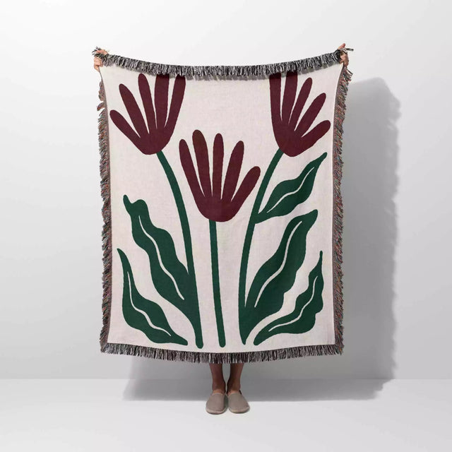 Floral patterned Matisse style red flowers woven throw blanket with red flowers and green leaves on a white background