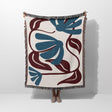 Decorative Matisse style red and blue cotton woven throw blanket with blue and brown floral pattern on a white background