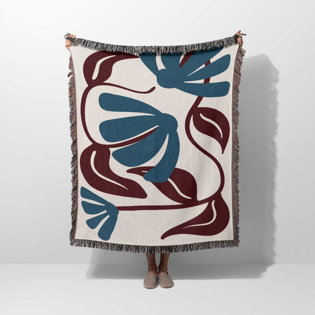 Decorative Matisse style red and blue cotton woven throw blanket with blue and brown floral pattern on a white background
