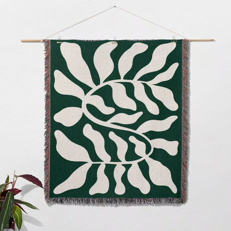 Matisse throw blanket green leaf abstract tapestry as a woven wall art hanging on a white wall.
