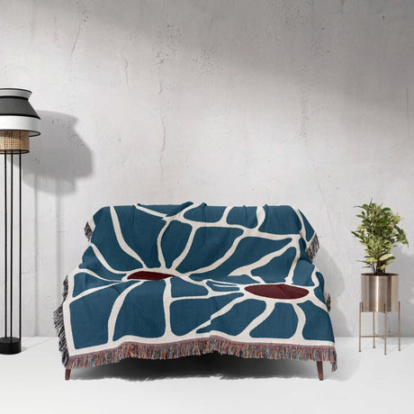 Maximalist Matisse inspired tapestry throw blanket for couch draped over a couch against a white wall.