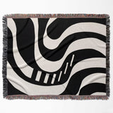 Black and white modern abstract art woven blanket throw tapestry flat lay on a white background.