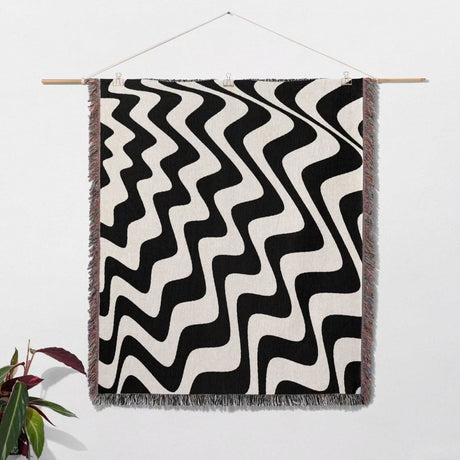 Black and white modern abstract waves woven blanket throw tapestry hanging on a wall.