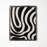 Black and white modern abstract woven blanket throw tapestry with fringe full view on a light gray background