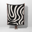 Black and white modern abstract woven blanket throw tapestry held by a person on a white background