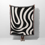 Black and white modern abstract woven blanket throw tapestry held by a person on a white background