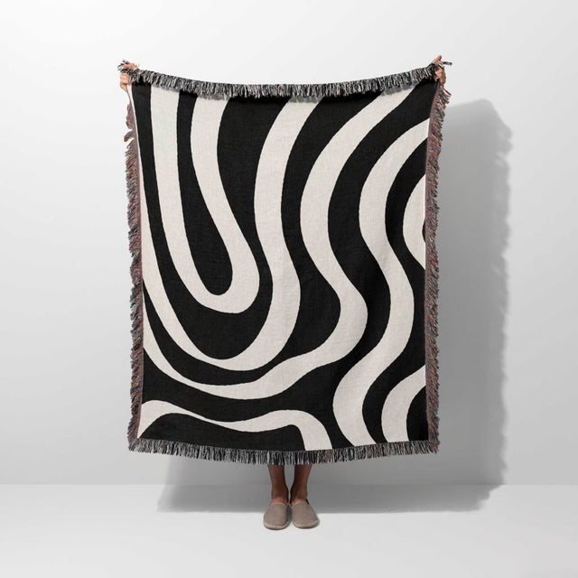 Black and white modern abstract woven blanket throw tapestry held by a person on a white background