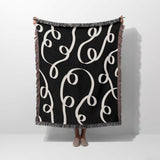 Black and white modern accent woven blanket throw tapestry held by a person on a white background