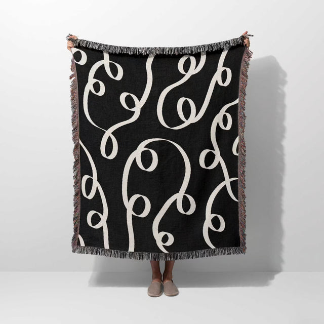 Black and white modern accent woven blanket throw tapestry held by a person on a white background