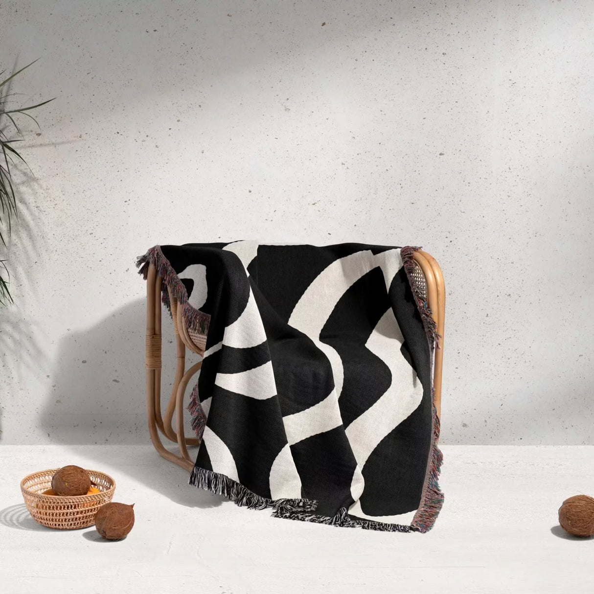 Black and white modern aesthetic waves woven blanket throw draped over a wooden chair on a light background.