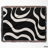 Black and white modern aesthetic waves woven blanket throw with fringed  flat lay edges on a white background.