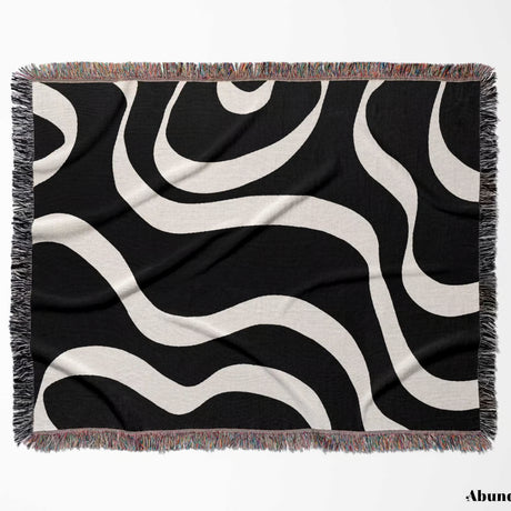 Black and white modern aesthetic waves woven blanket throw with fringed  flat lay edges on a white background.