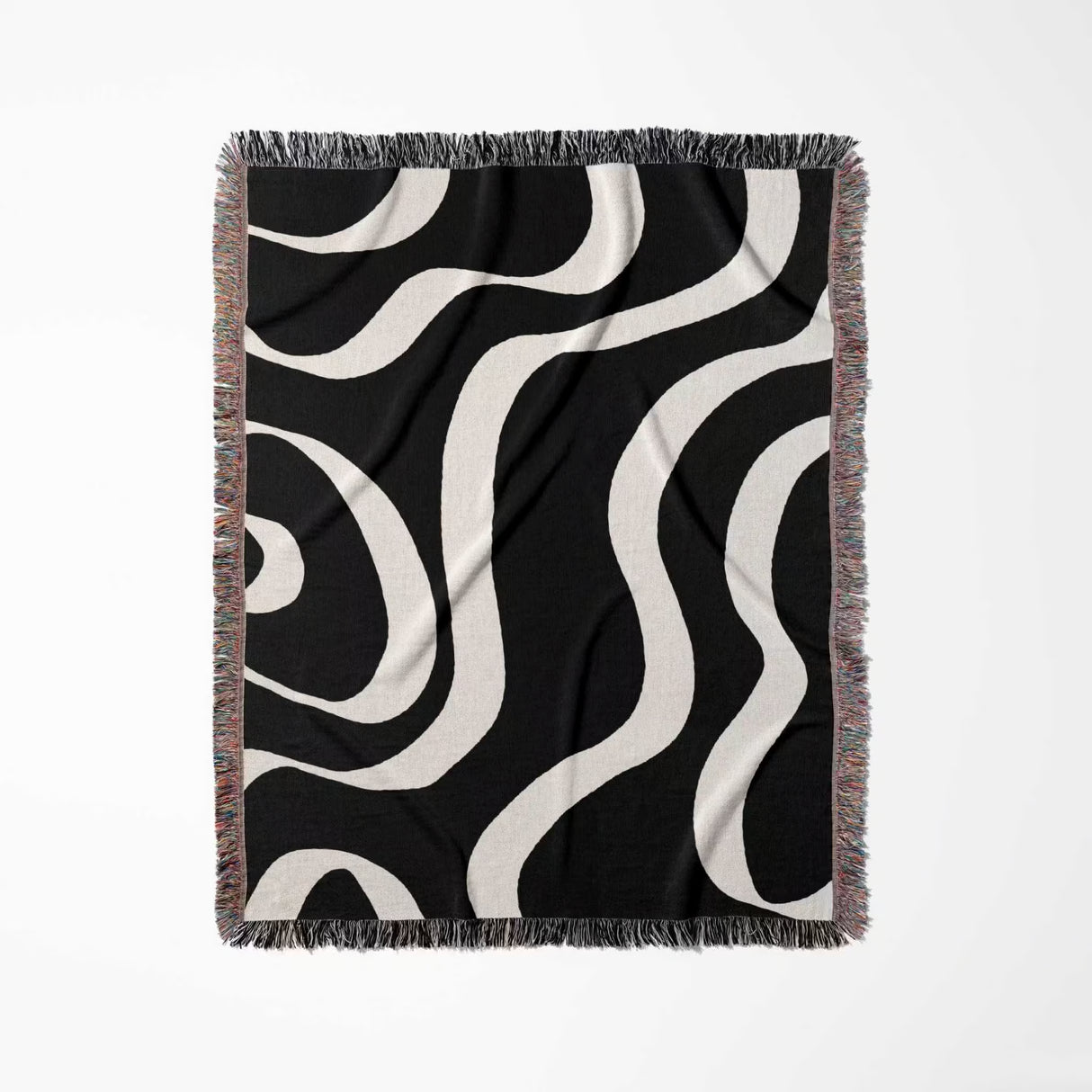 Black and white modern aesthetic waves woven blanket throw with fringed edges flat lay on a light gray background.