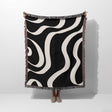 Black and white modern aesthetic waves woven blanket throw held by a person on a white background.