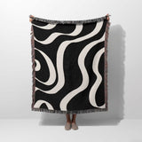 Black and white modern aesthetic waves woven blanket throw held by a person on a white background.