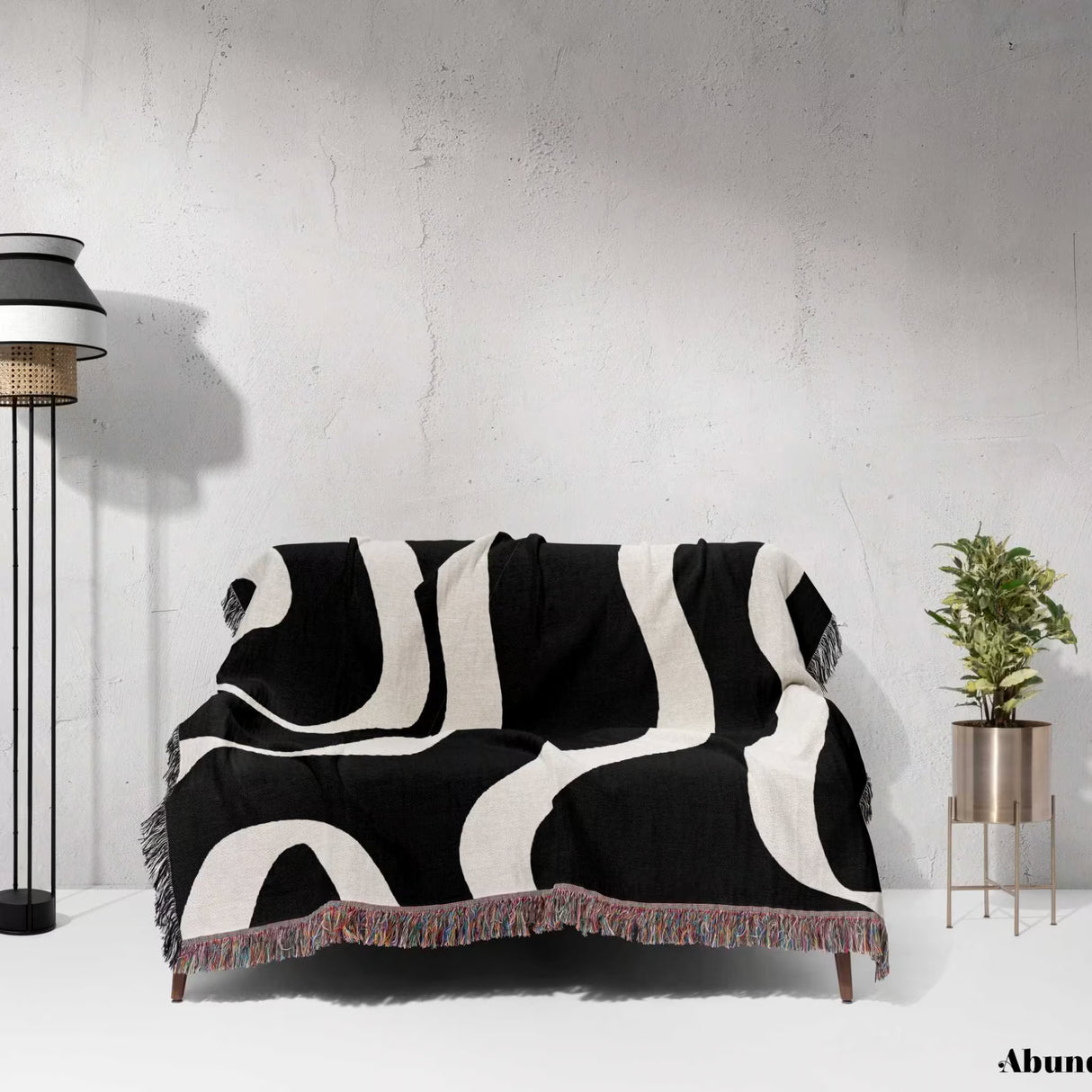 Black and white modern aesthetic waves woven blanket throw draped over a sofa against a white wall.