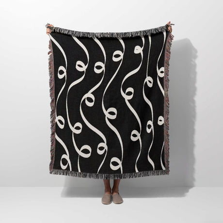 Black and white modern art decorative woven blanket throw tapestry held by a person on a white background